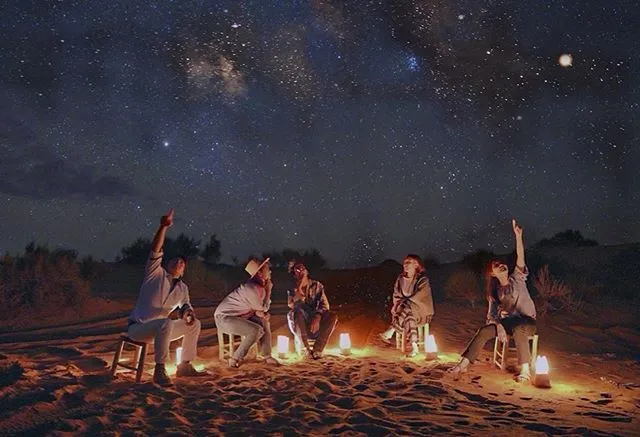 people sitting under stars in the desert of abu dhabi and enjoying overnight desert safari abu dhabi
